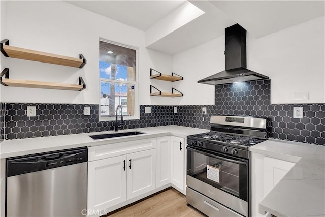 kitchen featuring sink, appliances with stainless steel finishes, extractor fan, light hardwood / wood-style floors, and white cabinets