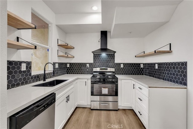 kitchen featuring sink, stainless steel appliances, white cabinets, wall chimney exhaust hood, and light wood-type flooring