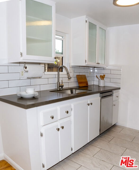 kitchen featuring sink, decorative backsplash, stainless steel dishwasher, and white cabinets