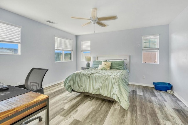 bedroom featuring multiple windows, hardwood / wood-style flooring, and ceiling fan