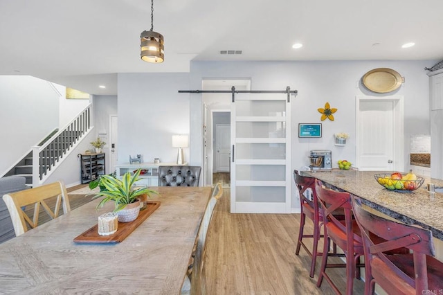 dining area with light hardwood / wood-style flooring and a barn door