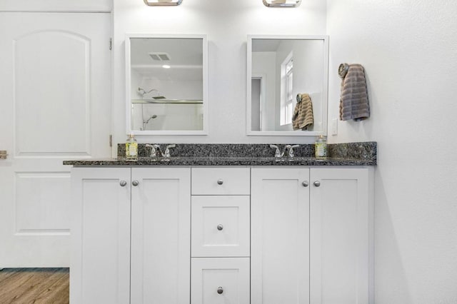 bathroom with hardwood / wood-style flooring, vanity, and a shower with door