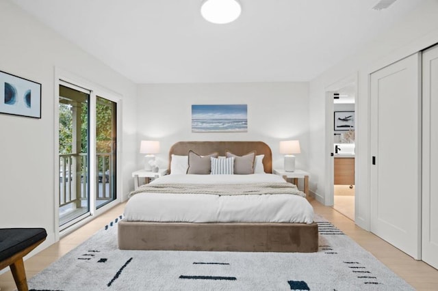 bedroom featuring ensuite bath, access to outside, and light wood-type flooring