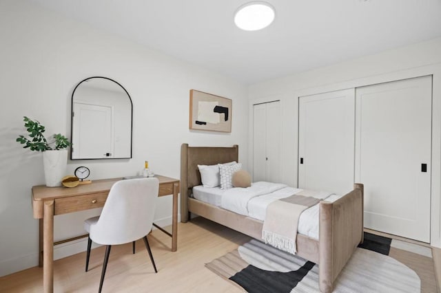 bedroom featuring multiple closets and light hardwood / wood-style floors