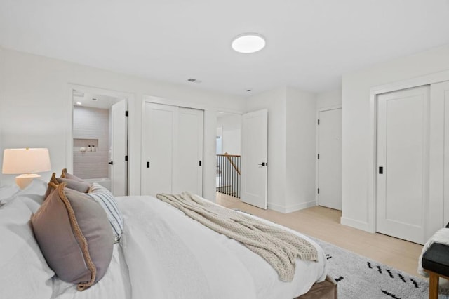 bedroom with two closets and light wood-type flooring