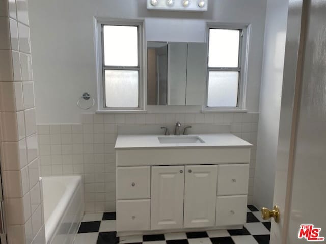 bathroom featuring tile walls, a tub to relax in, and vanity