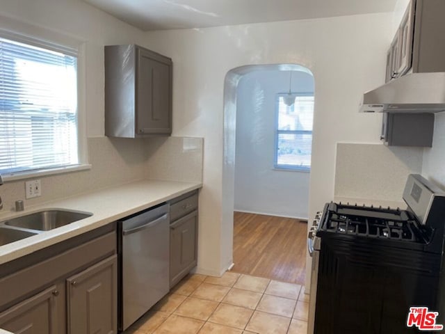 kitchen with stainless steel appliances, gray cabinetry, a wealth of natural light, and light tile patterned floors