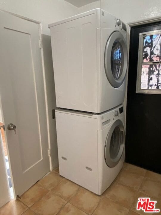 clothes washing area featuring stacked washer and dryer and light tile patterned floors