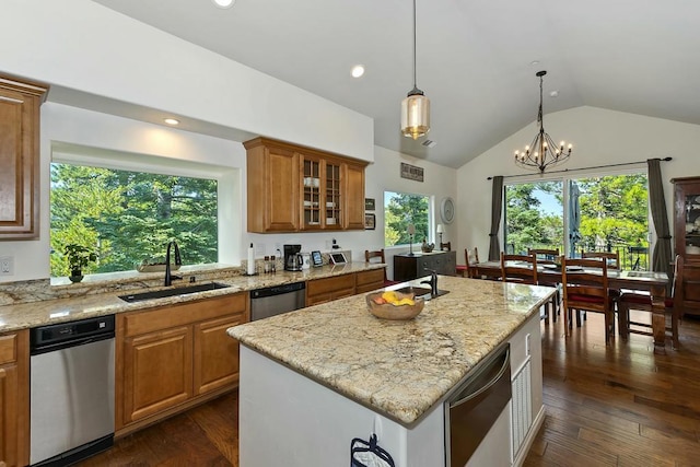 kitchen with light stone counters, dishwasher, sink, and a center island with sink