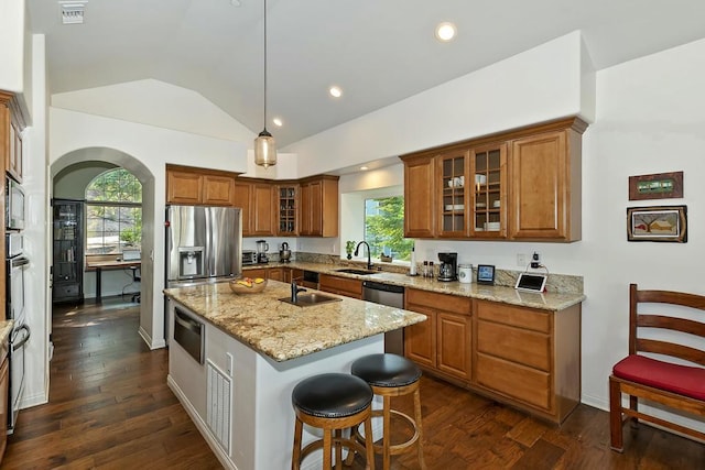 kitchen featuring lofted ceiling, sink, light stone counters, a center island with sink, and pendant lighting