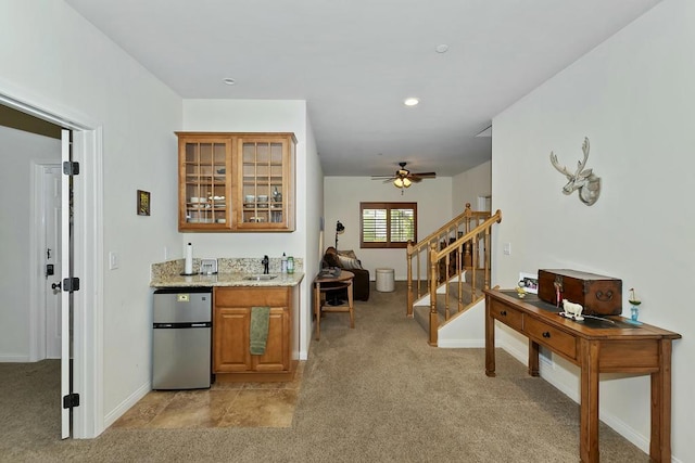 kitchen featuring stainless steel refrigerator, light stone countertops, and light carpet