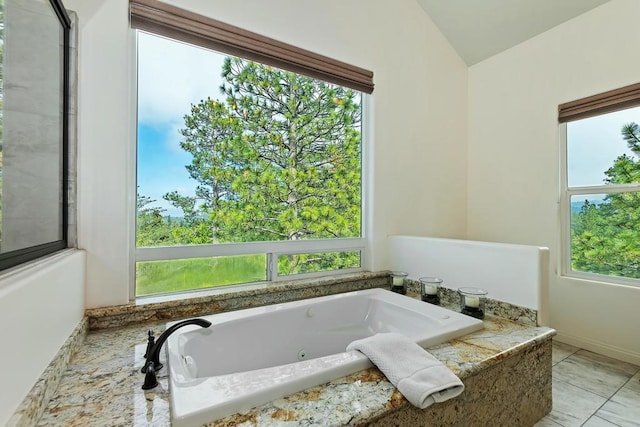 bathroom with lofted ceiling, tiled tub, and a wealth of natural light