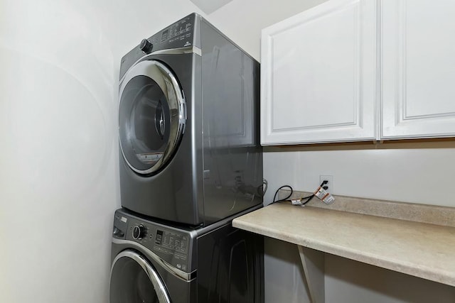 washroom featuring cabinets and stacked washer and clothes dryer