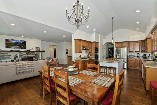 dining space featuring high vaulted ceiling, sink, dark wood-type flooring, and a chandelier