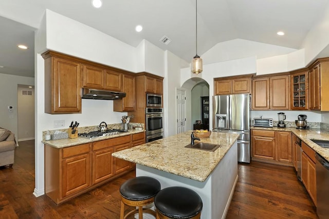 kitchen with appliances with stainless steel finishes, pendant lighting, sink, a breakfast bar area, and a center island