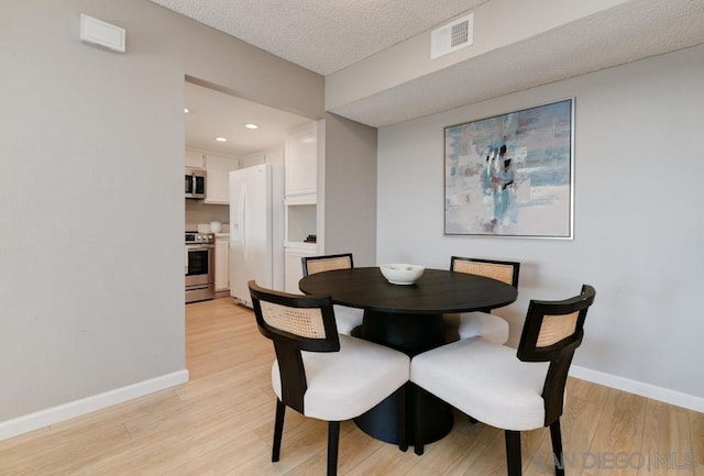 dining area featuring a textured ceiling and light wood-type flooring