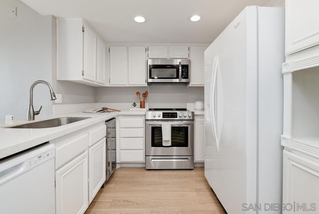 kitchen featuring white cabinetry, sink, light wood-type flooring, and appliances with stainless steel finishes