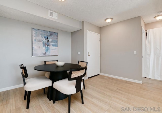 dining space featuring a textured ceiling and light hardwood / wood-style floors