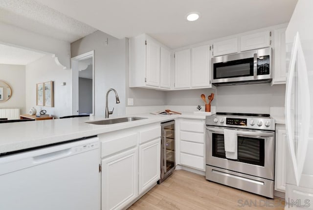 kitchen with wine cooler, sink, white cabinetry, stainless steel appliances, and light hardwood / wood-style floors