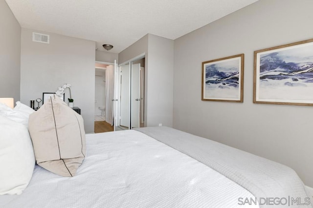 bedroom with ensuite bath and a textured ceiling