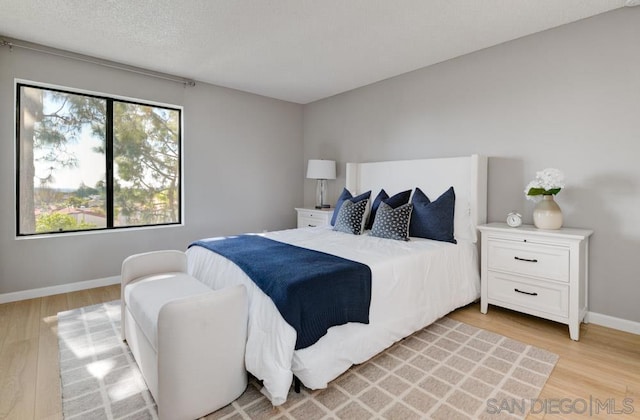 bedroom with light hardwood / wood-style floors and a textured ceiling