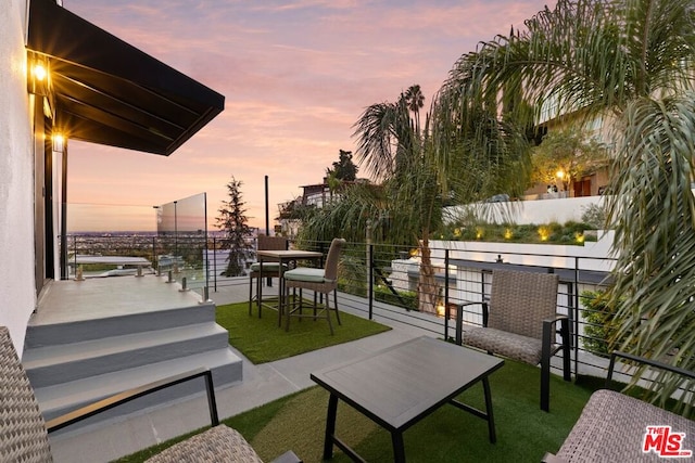 patio terrace at dusk featuring a balcony