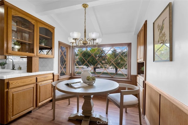 dining room featuring dark hardwood / wood-style flooring, vaulted ceiling with beams, sink, and a chandelier