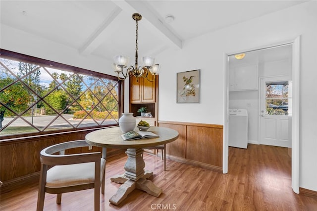 dining room featuring beam ceiling, a notable chandelier, washer / dryer, and hardwood / wood-style flooring