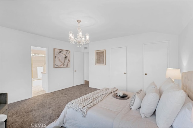 bedroom with an inviting chandelier, ensuite bath, lofted ceiling, and carpet flooring