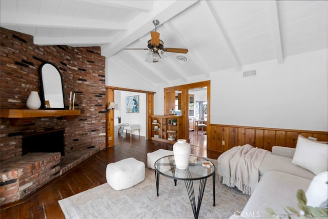 living room featuring ceiling fan, a fireplace, dark hardwood / wood-style flooring, and vaulted ceiling with beams