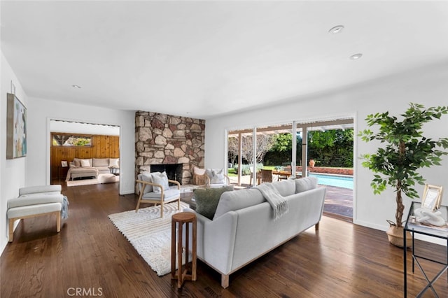 living room featuring dark wood-type flooring and a stone fireplace