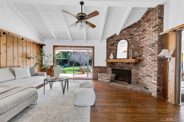 living room with ceiling fan, a brick fireplace, vaulted ceiling with beams, and dark hardwood / wood-style floors