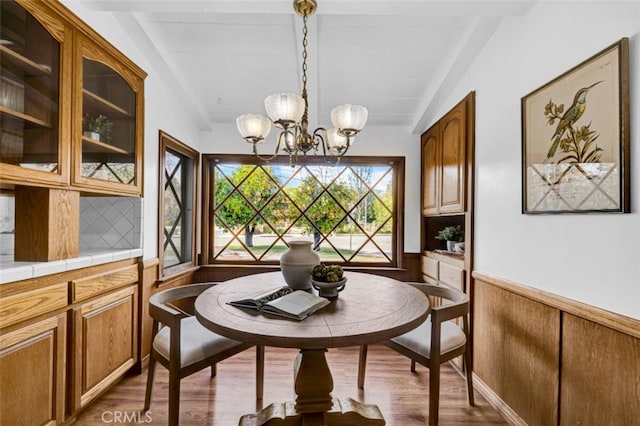 dining space with dark hardwood / wood-style floors, a chandelier, and vaulted ceiling with beams