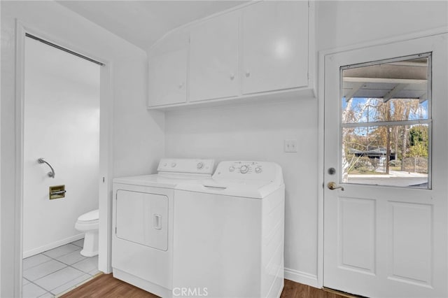 clothes washing area with cabinets, light hardwood / wood-style floors, and washer and dryer