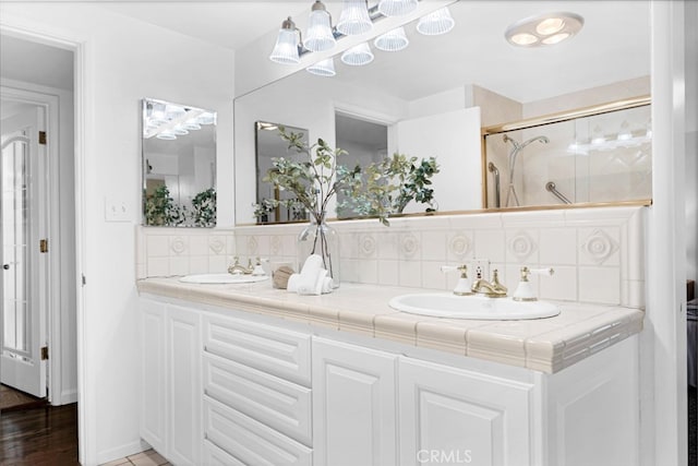 bathroom featuring vanity, backsplash, and a shower with shower door