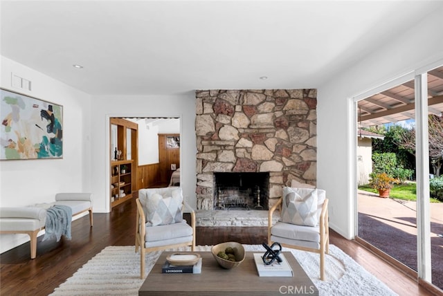 living room featuring a stone fireplace and dark hardwood / wood-style floors