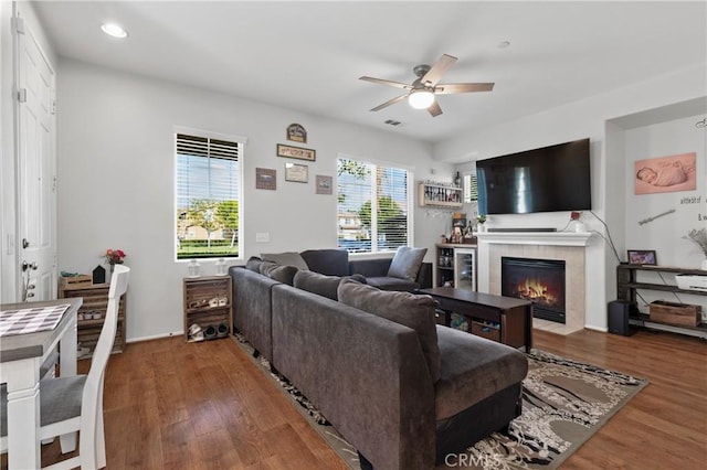 living room with wood-type flooring, a tile fireplace, and ceiling fan