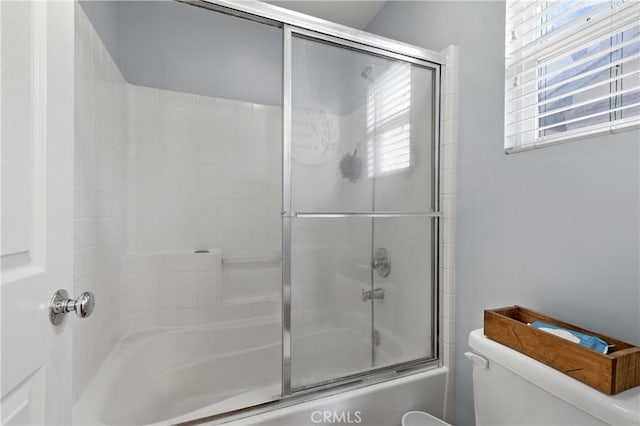 bathroom featuring enclosed tub / shower combo and toilet