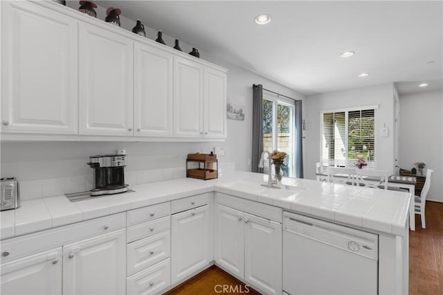 kitchen with tile countertops, dishwasher, sink, white cabinets, and kitchen peninsula