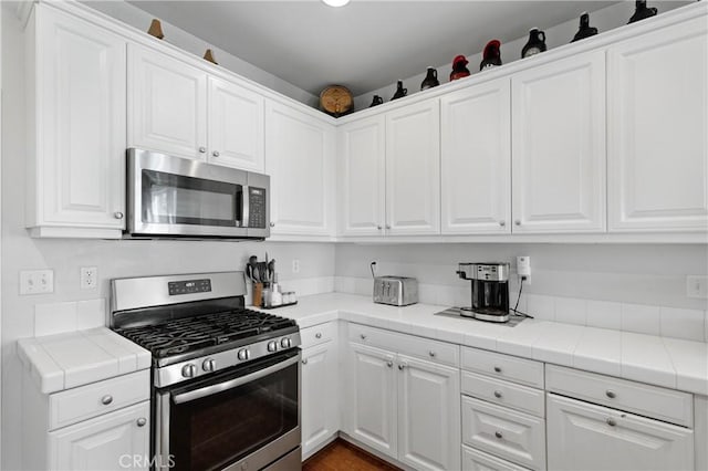 kitchen featuring white cabinetry, appliances with stainless steel finishes, and tile countertops