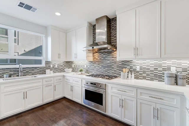 kitchen featuring white cabinets, stainless steel appliances, and wall chimney exhaust hood