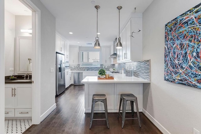 kitchen with appliances with stainless steel finishes, white cabinets, a kitchen breakfast bar, and kitchen peninsula