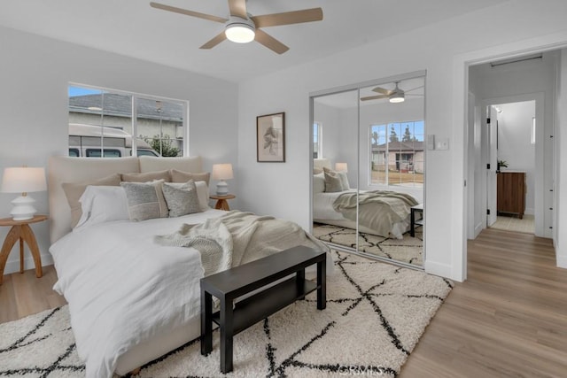 bedroom featuring ceiling fan, light hardwood / wood-style floors, and multiple windows