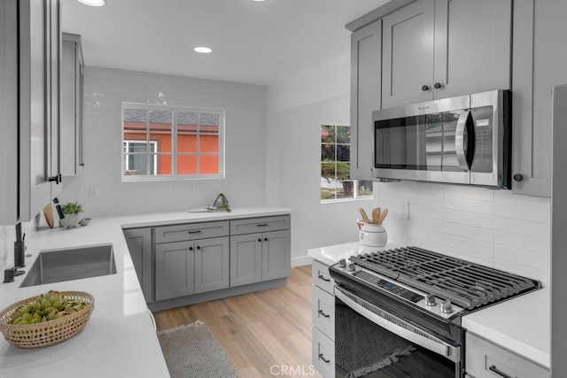 kitchen featuring tasteful backsplash, sink, light hardwood / wood-style flooring, and stainless steel appliances