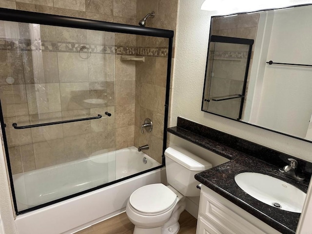 full bathroom featuring toilet, vanity, bath / shower combo with glass door, and hardwood / wood-style floors