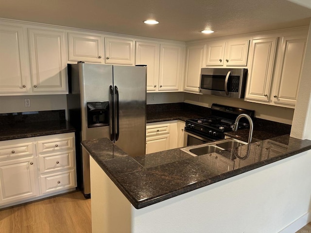 kitchen featuring light hardwood / wood-style flooring, kitchen peninsula, white cabinets, and appliances with stainless steel finishes