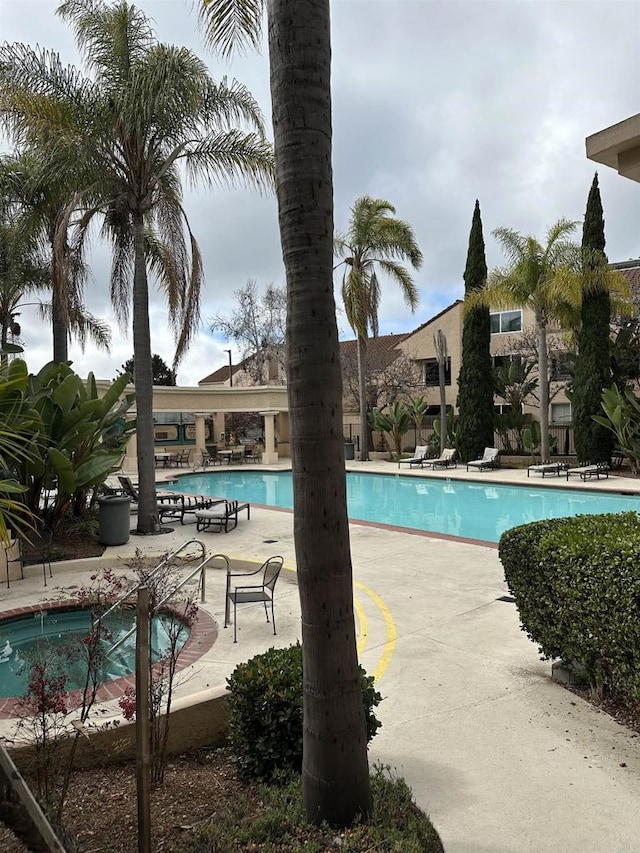 view of swimming pool featuring a jacuzzi and a patio