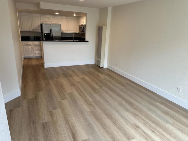 kitchen with appliances with stainless steel finishes, light wood-type flooring, and white cabinets