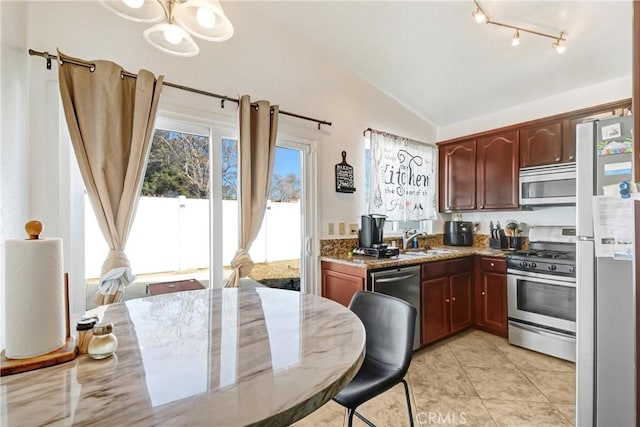 kitchen featuring lofted ceiling, sink, light tile patterned floors, appliances with stainless steel finishes, and light stone countertops