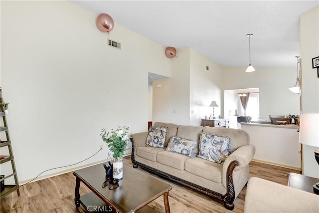 living room featuring lofted ceiling and light hardwood / wood-style floors